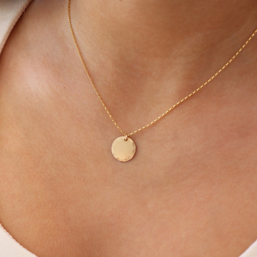 Model Wearing Mini Coin Necklace. This Necklace features a coin disc hammered on the outside of the circle. it slides around on the coin necklace chain.