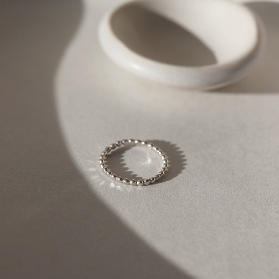 925 Sterling silver Sequin Ring placed on a white plate in the sunlight. This ring features our sequin band. This ring is perfect for stacking and everyday wear.