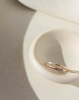 14k gold fill stacking ring laid on white plate in the sunlight. This ring features a simple band with hammering on the outside. 