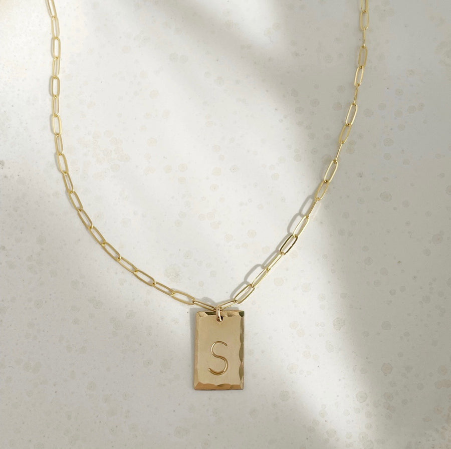 14k gold fill Everly Monogram Necklace placed on a white plate. Cosette linked chain - Gold or Sterling Silver Rectangle Hammered edge - Monogrammed with letter - Jewelry near me - Eau Claire