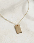 14k gold fill Everly Monogram Necklace placed on a white plate. Simple chain - Gold or Sterling Silver Rectangle Hammered edge - Monogrammed with letter - Jewelry near me - Eau Claire
