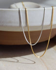 925 Sterling silver and 14k gold fill Necklace laid on a cream plate in the sunlight.