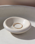 14k gold fill Minimal Ring Laid on a white ring dish. This ring features a simple band that is smooth, great for everyday wear.