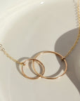 14k gold fill Unity Necklace laid on a white plate in the sunlight. 